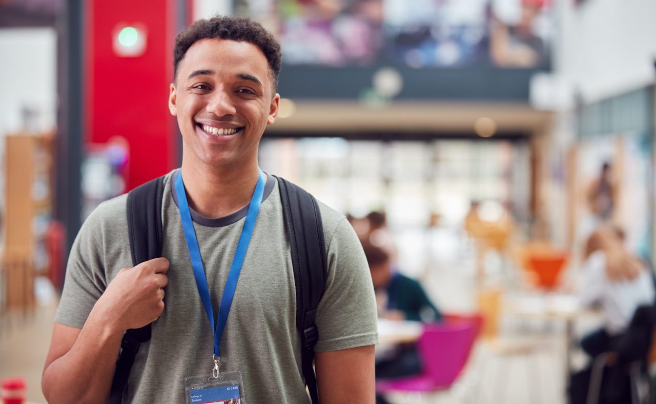 portrait-of-smiling-male-college-student-in-busy-communal-campus-building.jpg